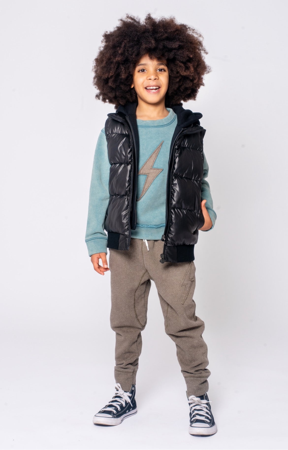 Young boy wearing the Turnstile Jacket in Black Steel, featuring a removable sleeve, front pockets, and a hood. Stylish and functional outerwear designed for playful adventures and changing weather.