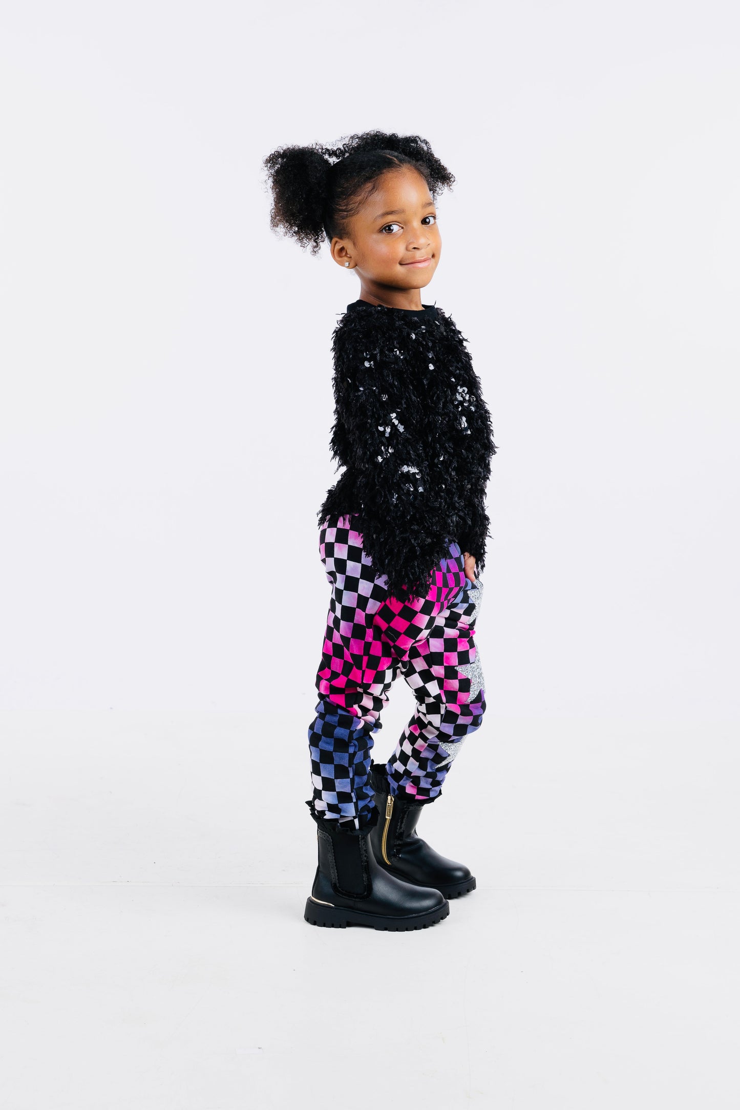 Trendy girls' checker joggers with a bold pink and purple tie-dye pattern, featuring a stylish checkerboard print and silver stars for added sparkle. Made from soft, stretchy fabric for comfort and versatility, with an elastic waistband for a secure fit. Perfect for casual wear or active days