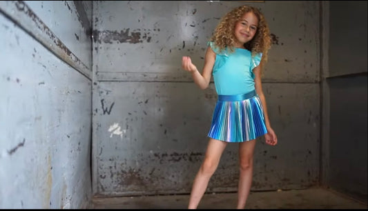 Girls pleated iridescent skort with shimmering fabric, featuring a classic silhouette, elastic waistband, and built-in shorts for comfort and style.