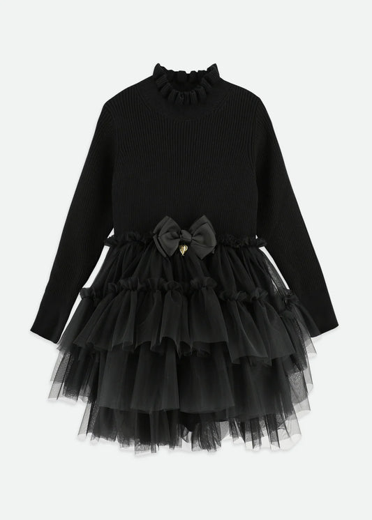 Elegant black ribbed jumper dress with layered soft tulle skirt and cotton lining. Features a frilled neck, signature bow, and gold heart charm on the waist.
